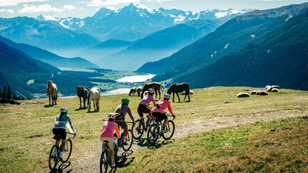 Das waren die Golden Days in Nauders © TVB-Tiroler-Oberland-Nauders-Christian-Penning - Gravelbiker mit Pferden am Reschensee Radfahrer fahren an weidenden Pferden vorbei über eine Almwiese vor Berggipfeln