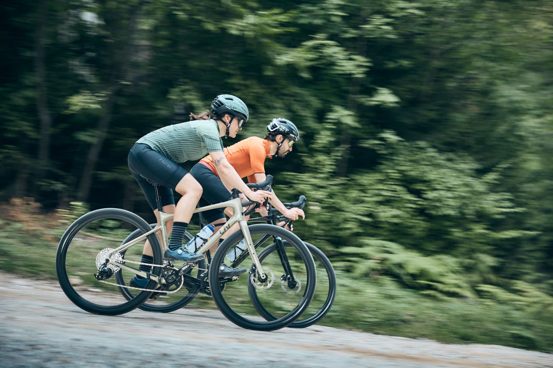Zwei Radfahrer in sportlicher Kleidung fahren auf einem Waldweg