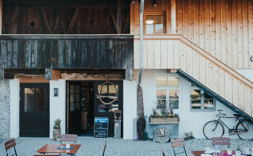 Eingang eines traditionellen Gasthauses mit Holzverkleidung und Sitzgelegenheiten außen