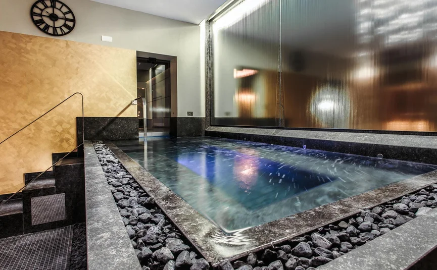 Moderner Innenwhirlpool mit steiniger Umrandung und beleuchtetem Wasser