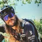 Francesco Guidi © Tenuta il Cicalino Mann mit Fahrradhelm und Sonnenbrille zeigt nach links und trägt Rucksack