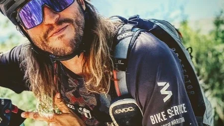 Gravelbiken in der Toskana © Tenuta il Cicalino Mann mit Fahrradhelm und Sonnenbrille zeigt nach links und trägt Rucksack