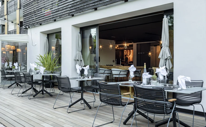 Modern outdoor terrace with set tables and chairs in front of a restaurant