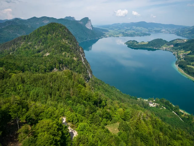 Drei Seen, eine Gravelrunde: Die 3-Seen-Tour ab Fuschl © Erwin Haiden Blick auf grünen Wald und blauen Bergsee unter bewölktem Himmel