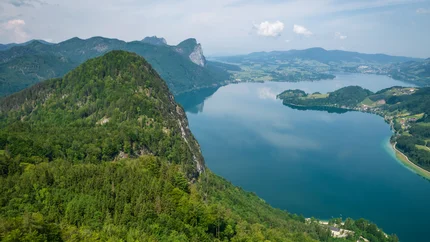 View of green forest and blue mountain lake under cloudy sky