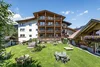 Large garden with tables, chairs, and loungers in front of alpine house