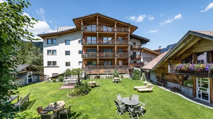 Großer Garten mit Tischen, Stühlen und Liegestühlen vor Alpenhaus