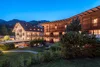Lit hotel buildings and garden at dusk in mountain landscape