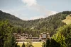 Hotel buildings nestled among green mountains and forest with a blue sky