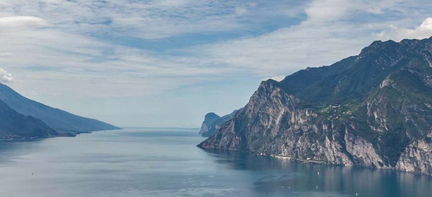 Blick auf einen Fjord mit steilen Bergen und bewölktem Himmel