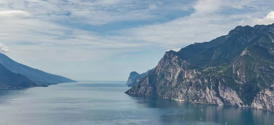 Blick auf einen Fjord mit steilen Bergen und bewölktem Himmel