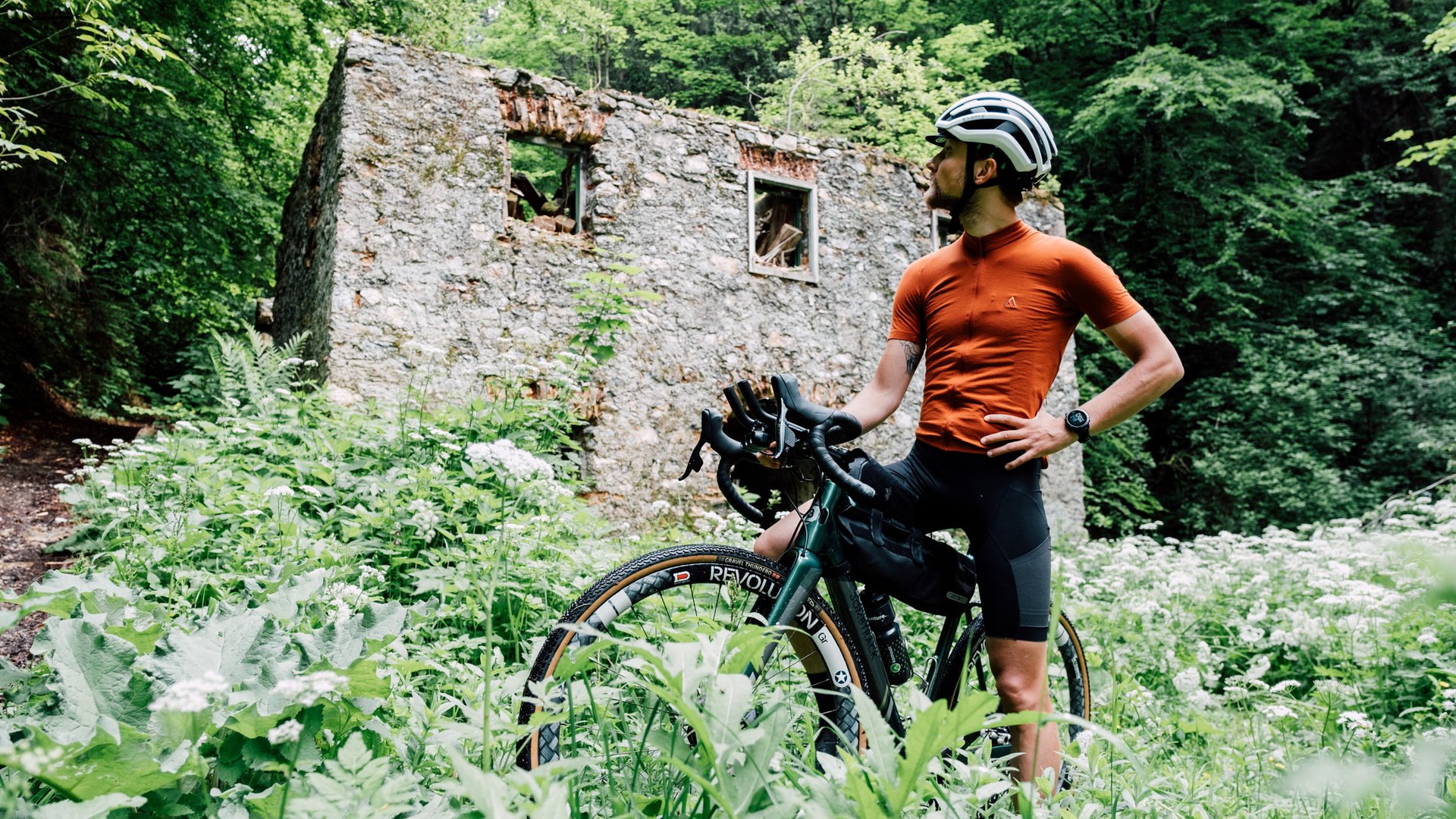 Radfahrer vor einer alten Ruine im dichten Grünen