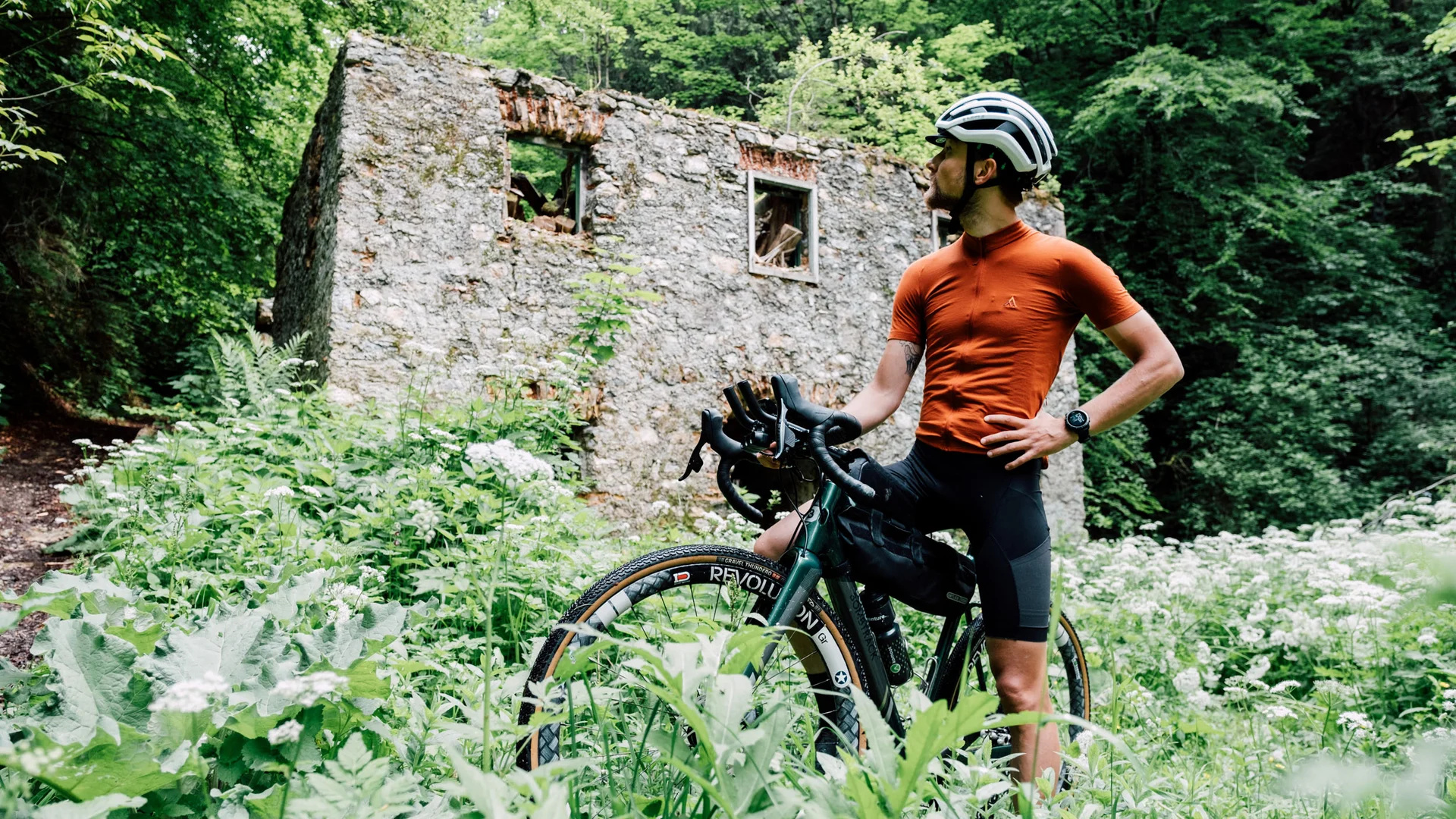 Radfahrer vor einer alten Ruine im dichten Grünen
