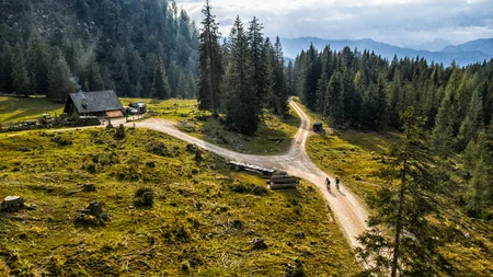 Zwei Radfahrer auf Weg in bewaldeter Berglandschaft mit Hütte