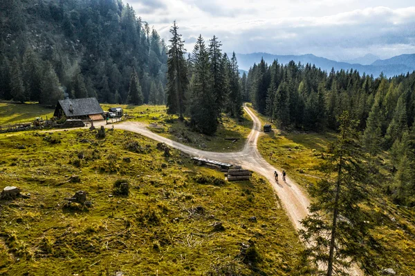 Austria © WOM Medien GMBH - Andreas Meyer Two cyclists on a trail in forested mountain area near a cabin