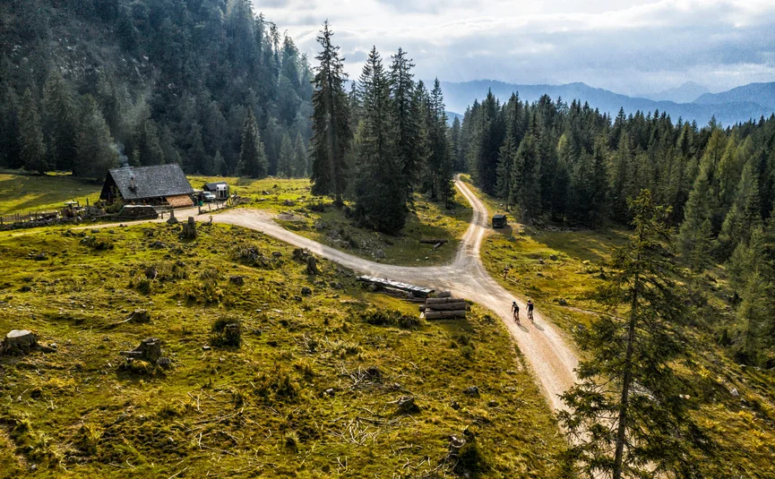 Gravelbike Urlaub in der Fuschlseeregion © WOM Medien GMBH - Andreas Meyer Zwei Radfahrer auf Weg in bewaldeter Berglandschaft mit Hütte