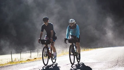 Zwei Radfahrer fahren auf einer Straße bei nebligem Wetter