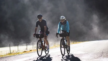 Two cyclists riding on a road in foggy weather
