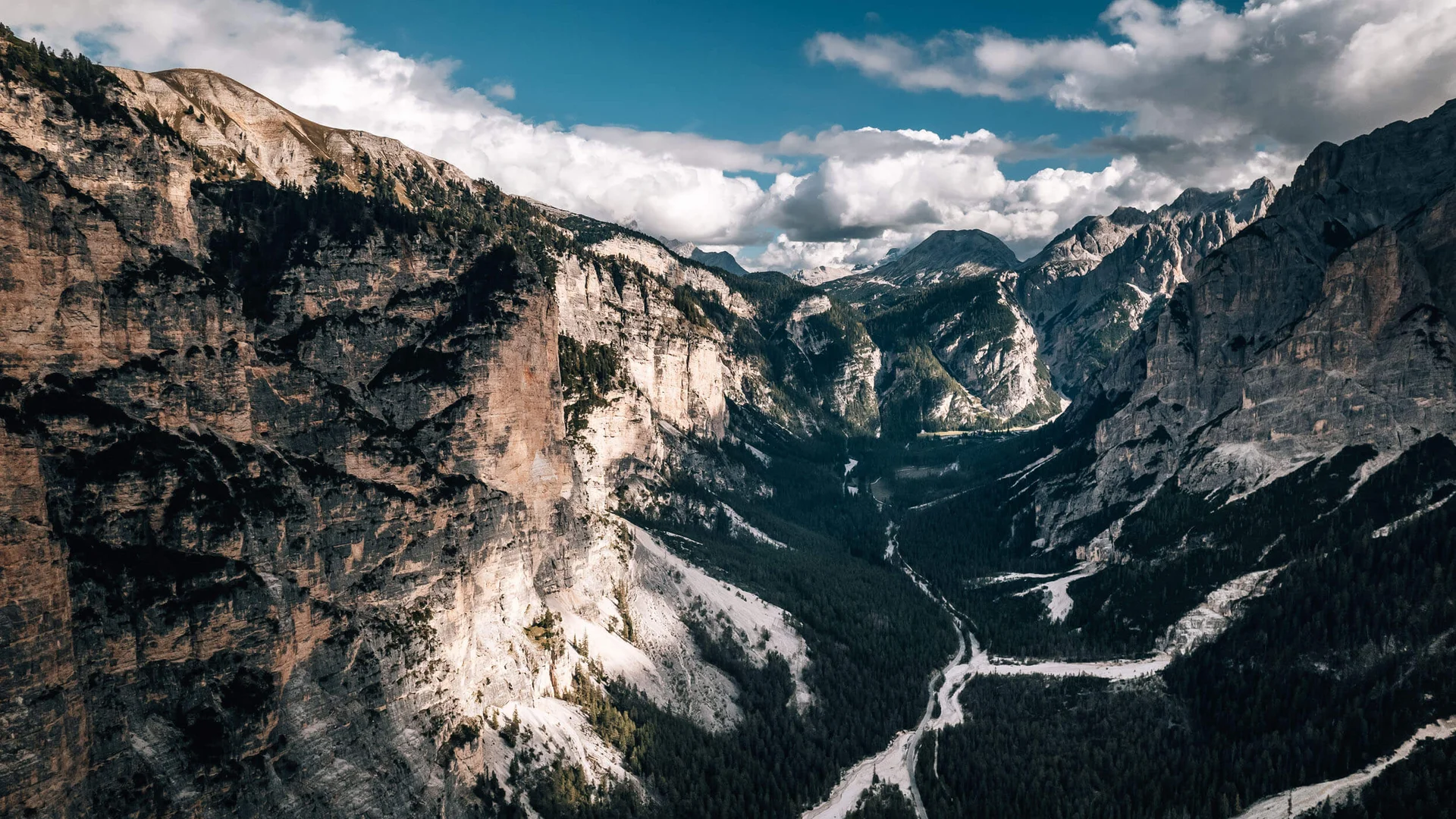 Bergtal mit steilen Felswänden und bewaldetem Talboden unter blauem Himmel