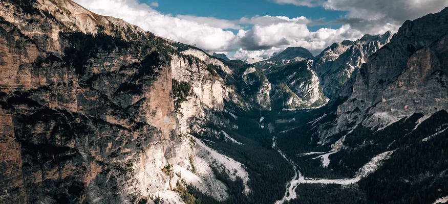 Bergtal mit steilen Felswänden und bewaldetem Talboden unter blauem Himmel