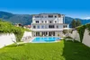 Modern white building with swimming pool and mountains in the background