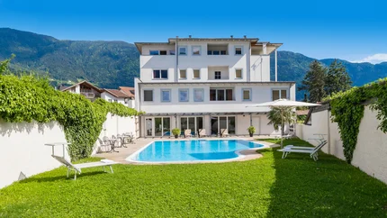 Modern white building with swimming pool and mountains in the background