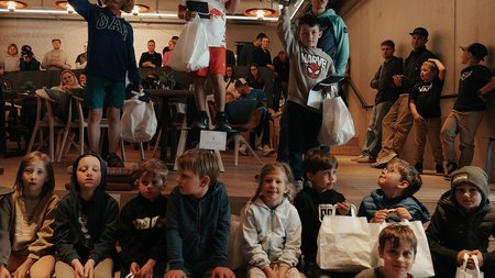 Kinder bei einer Siegerehrung mit Pokalen und Geschenktüten in einem Café