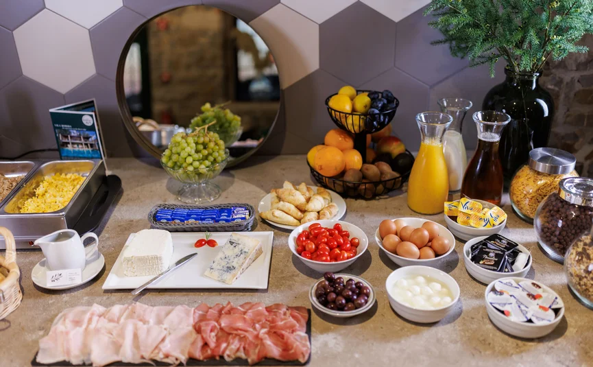 Breakfast buffet with cold cuts, cheese, fruit, eggs, cereals, and juices