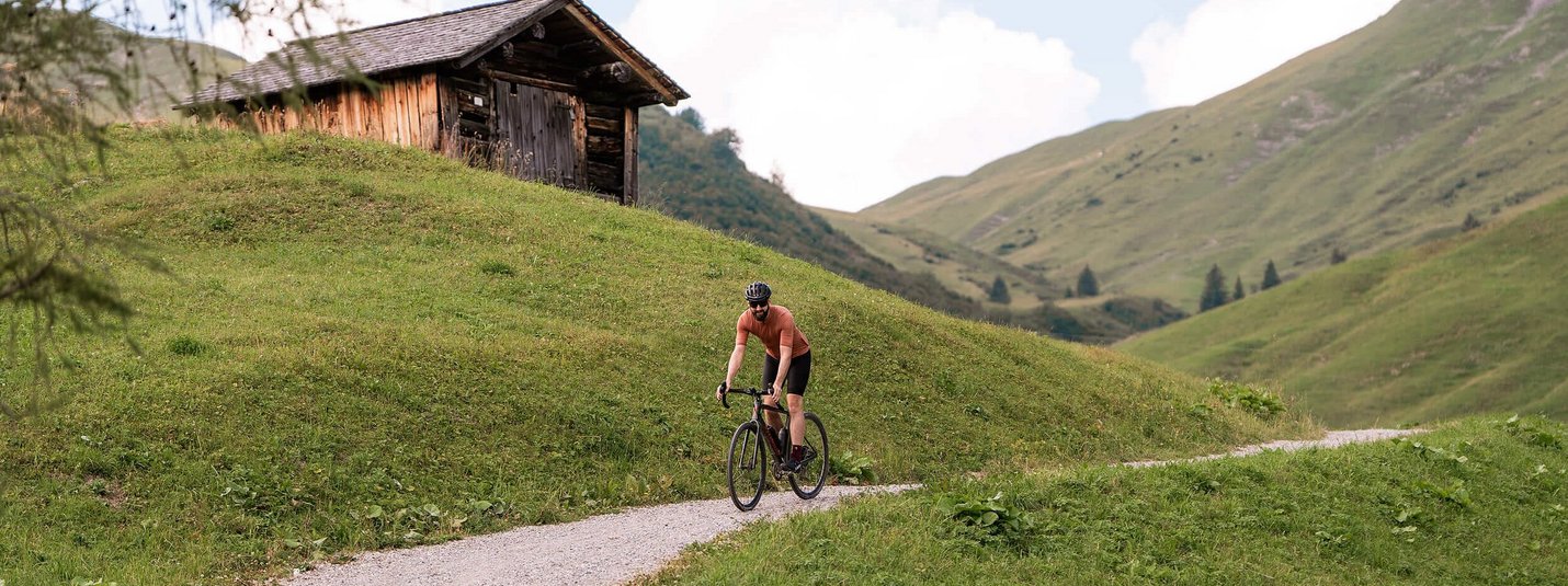 Lech and Zug to Formarinsee Gravel Tour © Janine Brugger - Vorarlberg Tourismus Man cycling on a mountain path near a wooden cabin