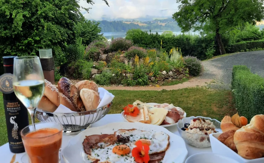 Frühstückstisch mit Eiern, Croissants und Getränken vor Gartenblick