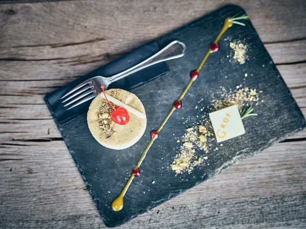 Qualitätsversprechen © Tobias Köhler Elegantes Dessert mit Kirsche, Nüssen und Schokoladendekor auf schwarzem Stein