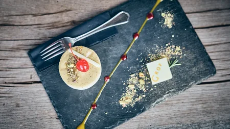 Elegant dessert with cherry, nuts, and chocolate decoration on black stone plate