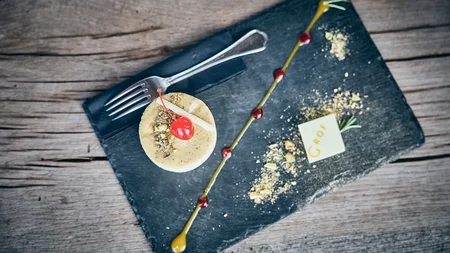 Qualitätsversprechen © Tobias Köhler Elegantes Dessert mit Kirsche, Nüssen und Schokoladendekor auf schwarzem Stein