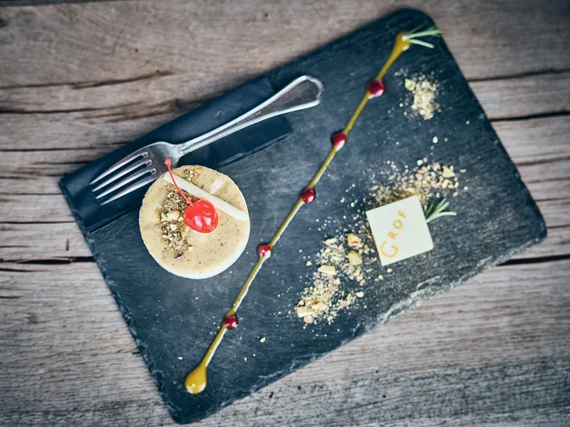 Elegant dessert with cherry, nuts, and chocolate decoration on black stone plate