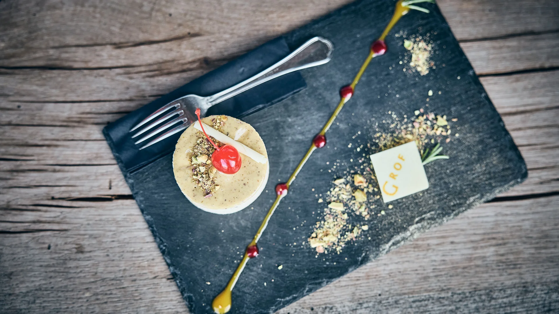 Elegantes Dessert mit Kirsche, Nüssen und Schokoladendekor auf schwarzem Stein