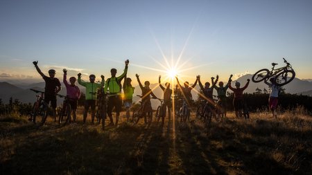 Gruppe von Radfahrern feiert bei Sonnenuntergang auf einem Berg