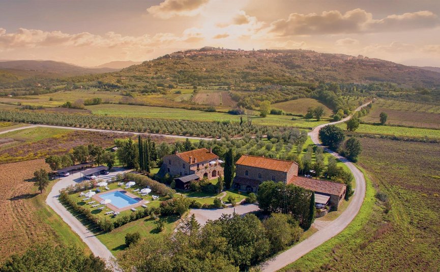 Luftaufnahme eines Bauernhauses mit Pool in einer grünen Hügellandschaft