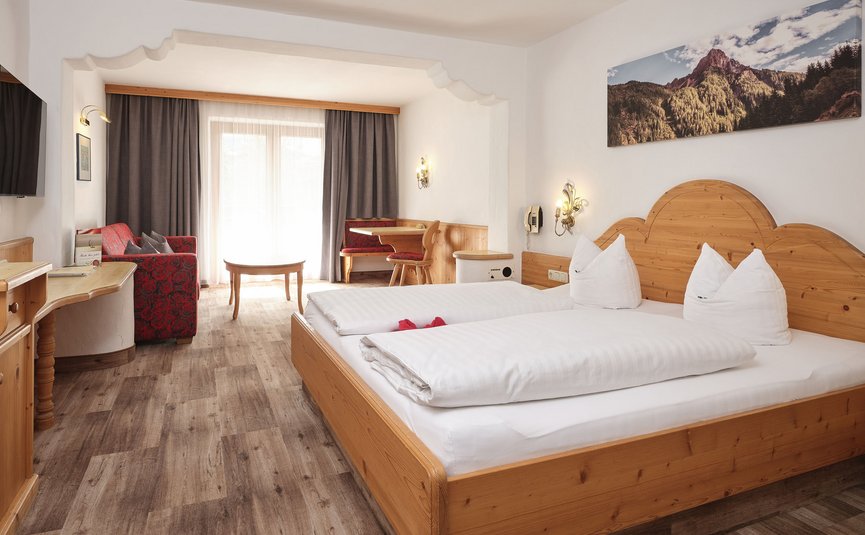 Gemütliches Hotelzimmer mit Doppelbett, Sitzecke und Bergbild an der Wand