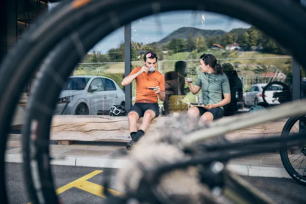 Angebote © Tobias Köhler Zwei Radfahrer trinken Kaffee auf Bank, Fahrradreifen im Vordergrund