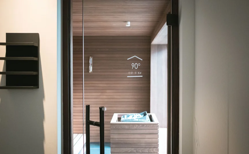 Glass sauna door with handle and wooden wall inside