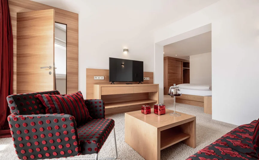 Modern eingerichtetes Wohnzimmer mit rotem Musterstuhl und Holzmöbeln