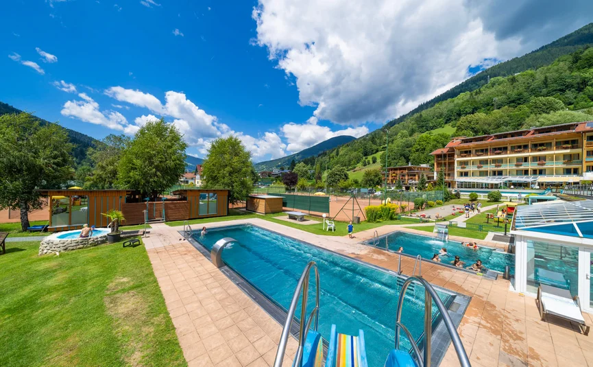 Außenpools und Tennisplätze in einer Bergresortanlage bei sonnigem Wetter