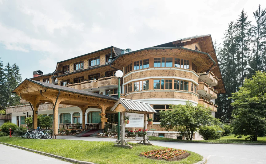 Cozy wooden hotel building with bike rack and green surroundings