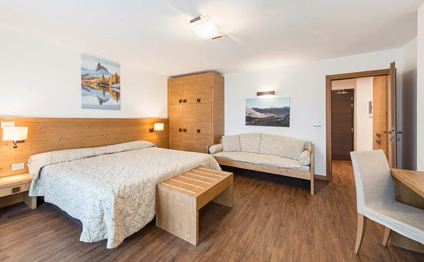Helles Hotelzimmer mit Doppelbett, Sofa und Holzmöbeln