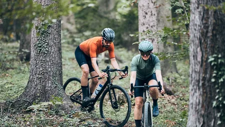 Qualitätsversprechen © Tobias Köhler Zwei Radfahrer fahren durch einen Wald auf einem schmalen Pfad