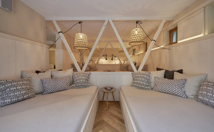 Gemütlicher Sitzbereich mit beigen Polstern, Kissen und hängender Korblampe