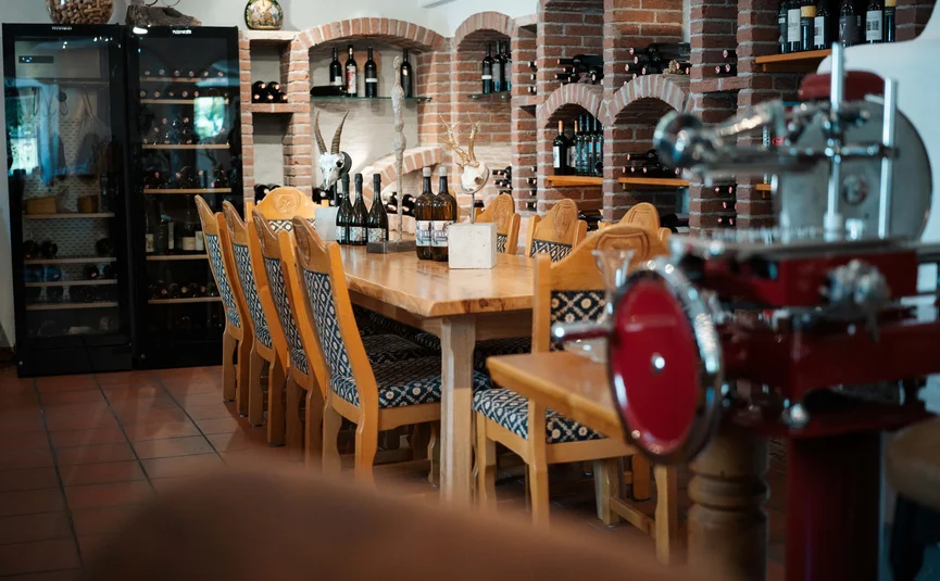 Bike Boutique Hotel Lindenhof **** © Martin Hofmann Weinkeller mit Holztisch, Stühlen und Weinflaschen in Ziegelnischen