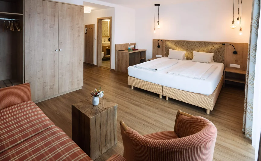 Modernes Hotelzimmer mit Doppelbett, Sitzbereich und Holzfußboden