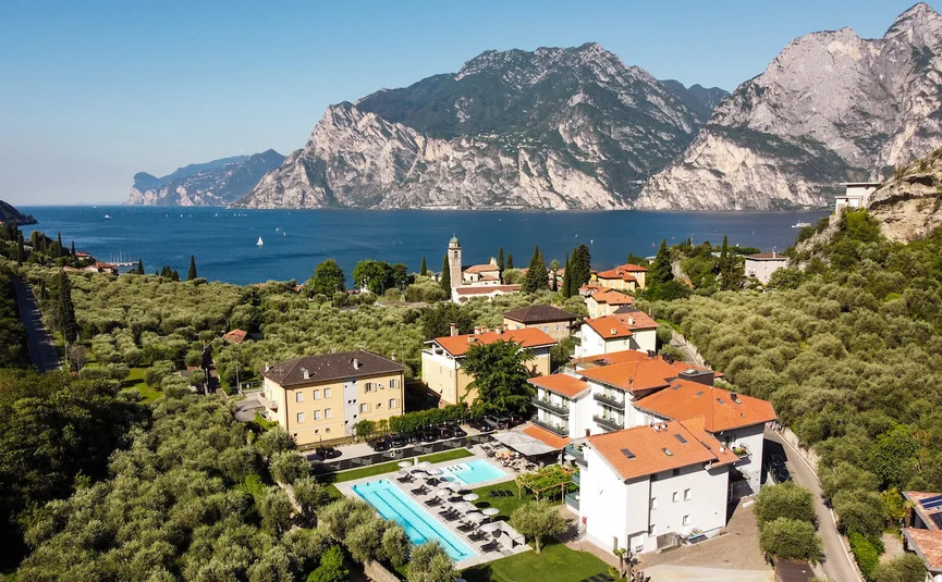 Village and hotel with pool by the lake surrounded by mountains