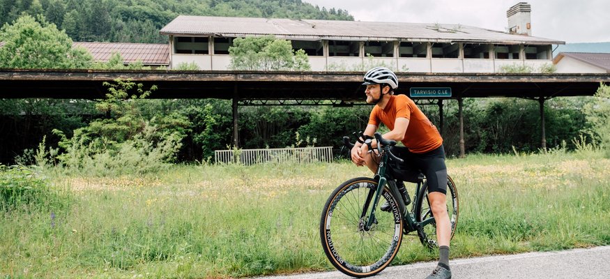 Radfahrer in Orange trinkt Pause neben Haus im grünen Gebiet